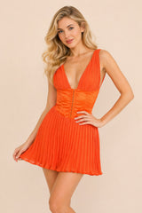 Robe courte sexy sans manches avec décolleté plongeant, bustier structuré et jupe plissée, portée par une femme.