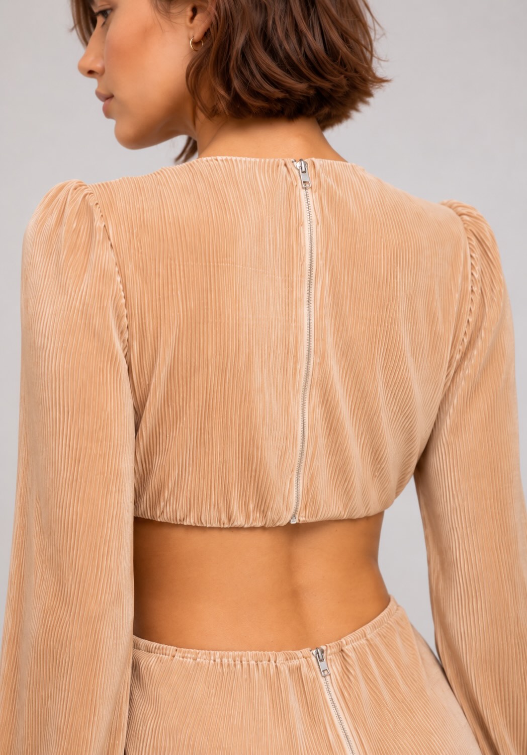 Combinaison plissée pour femme avec décolleté profond, découpes à la taille et boucle fleur, style chic et élégant.
