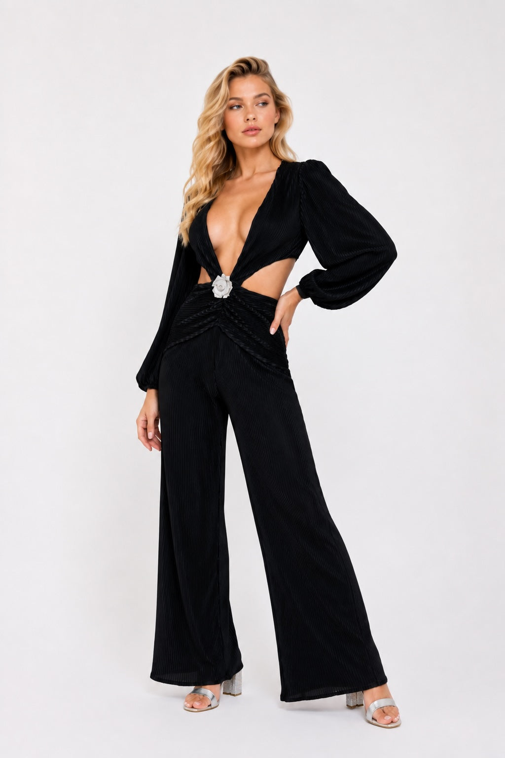 Combinaison femme plissée noire de Dressie Dress avec décolleté profond, découpes à la taille et boucle fleur, look élégant.