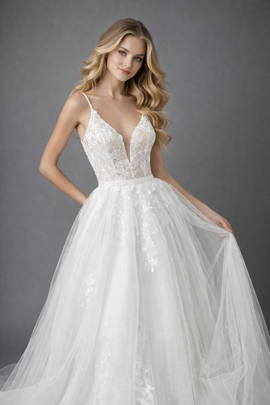 Robe de mariée en tulle illusion avec dentelle florale, décolleté plongeant, fines bretelles et grande jupe aérienne à traîne.
