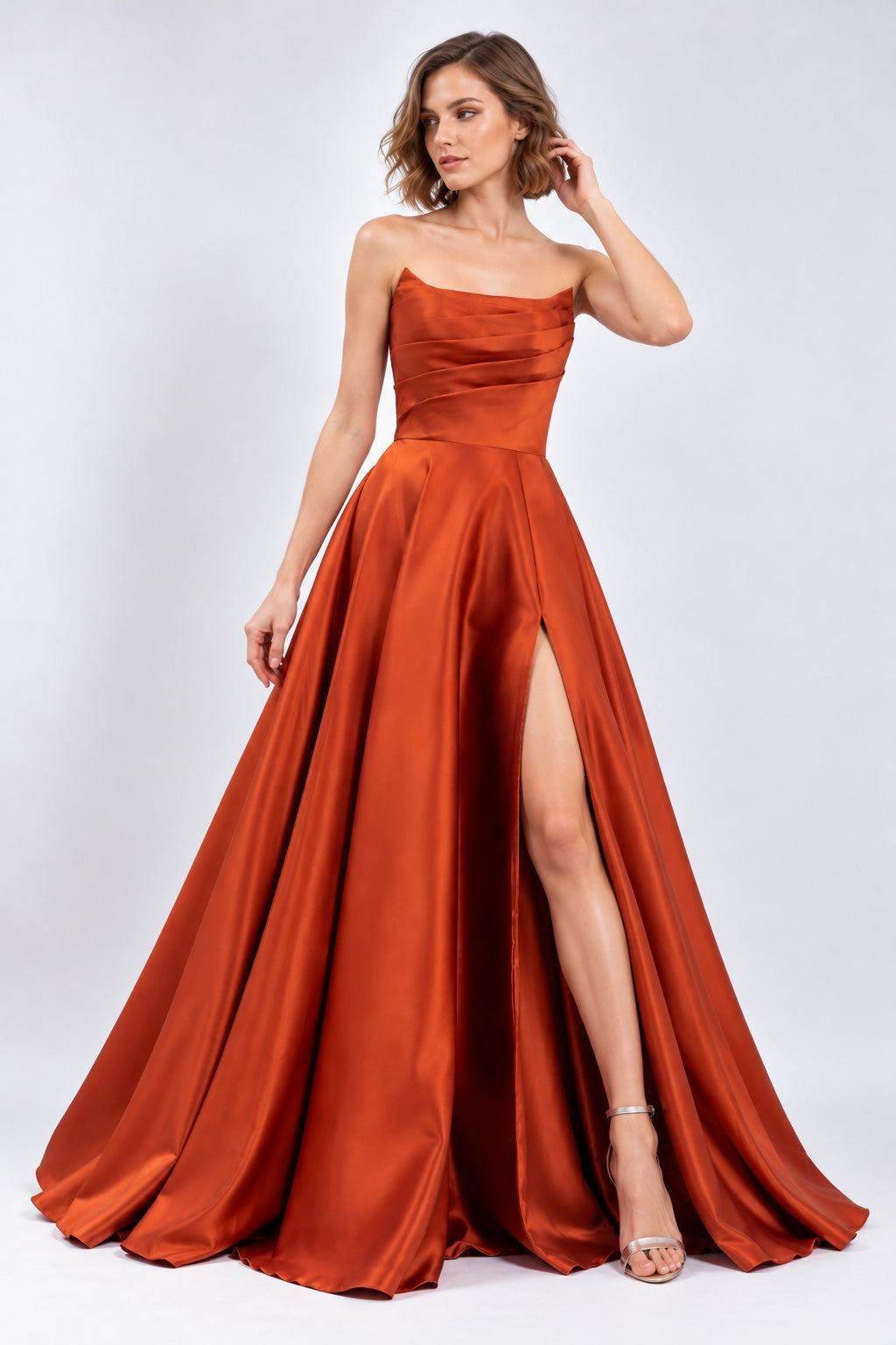 Robe de soirée bustier satinée Dressie Dress, robe structurée avec drapé, jupe volumineuse et fente élégante en couleur brique.