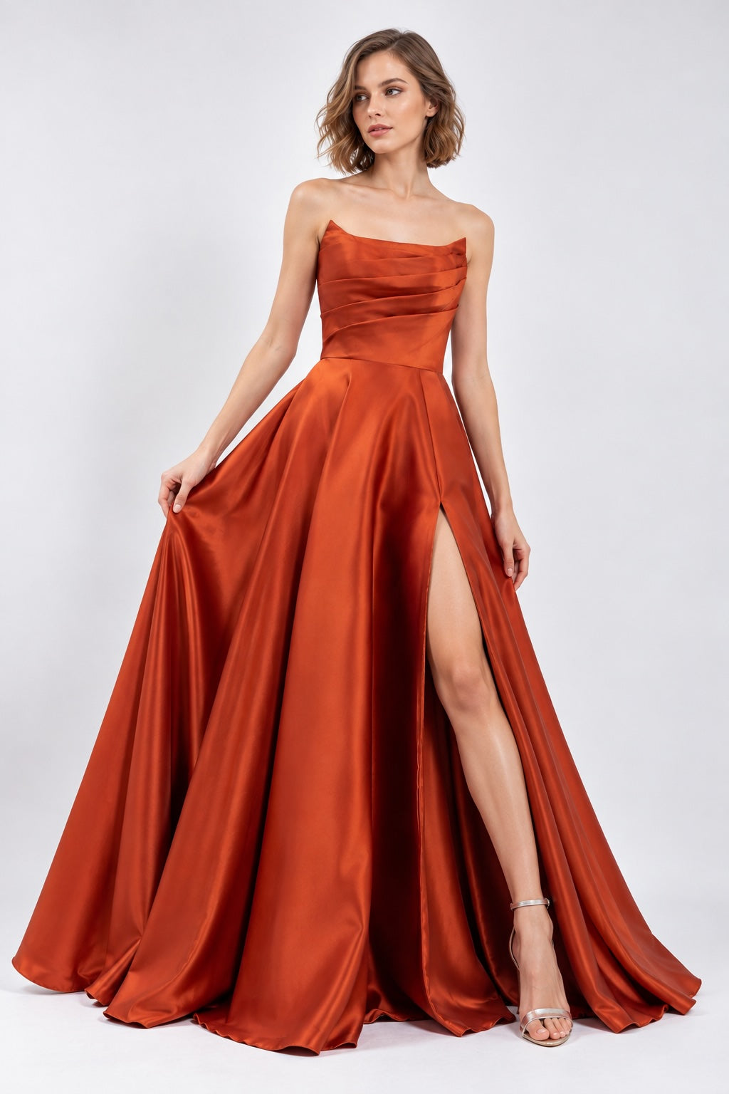 Robe de soirée bustier satinée rouge brique avec drapé structuré, jupe volumineuse et fente élégante, par Dressie Dress.