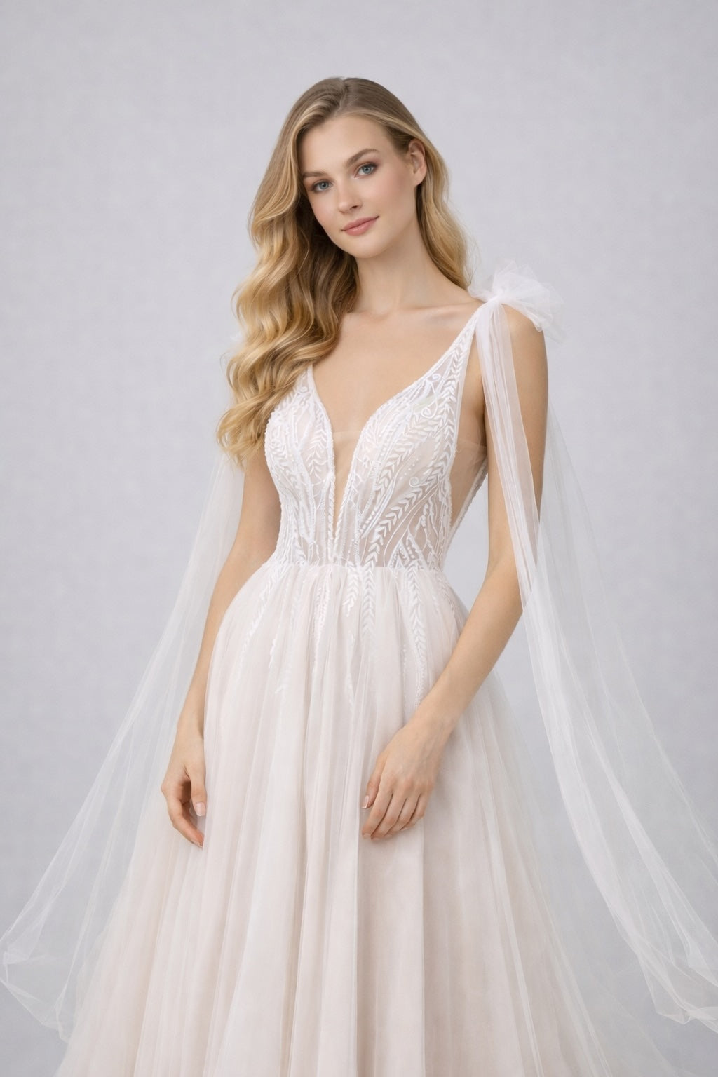 Robe de mariage Dressie avec décolleté plongeant, tulle brodé graphique, longues pans drapés pour cérémonie élégante.