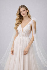 Robe de mariage Dressie avec décolleté plongeant, tulle brodé graphique, longues pans drapés pour cérémonie élégante.
