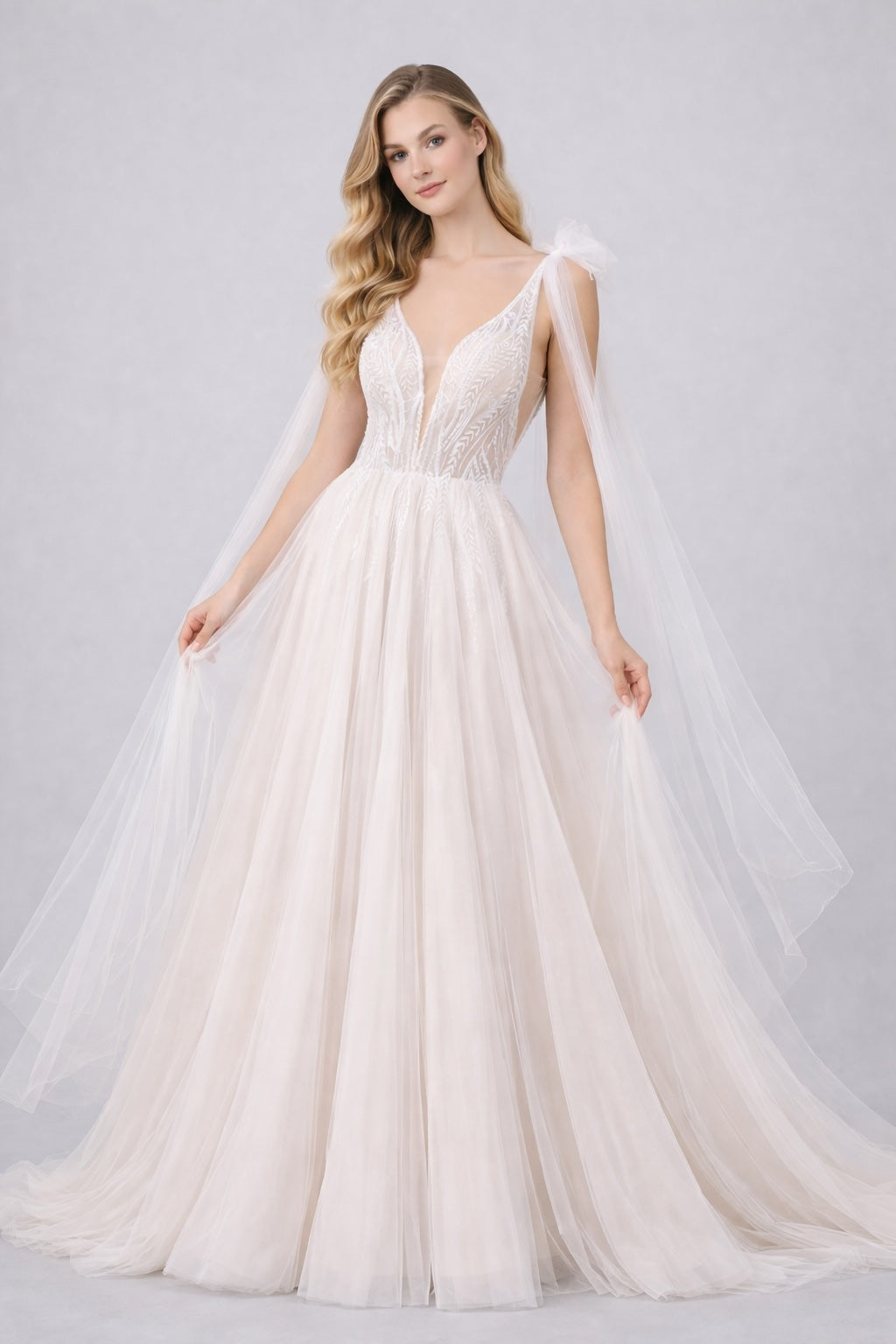 Robe de mariage Dressie à décolleté plongeant en tulle brodé avec pans drapés aux épaules, silhouette aérienne pour cérémonie nuptiale.