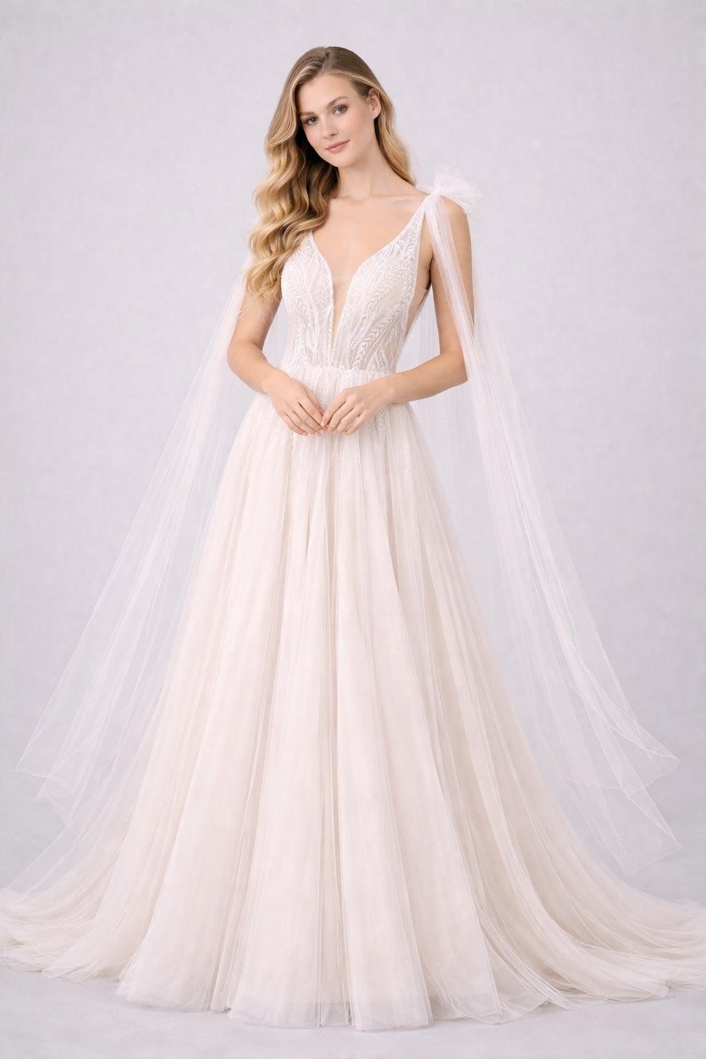 Robe de mariée en tulle illusion avec décolleté plongeant, broderies graphiques et longs pans drapés aux épaules. Dressie Dress.