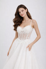 Robe de mariage Dressie Dress avec bretelles fines, corsage transparent brodé fleurs, grande jupe à traîne, silhouette élégante.